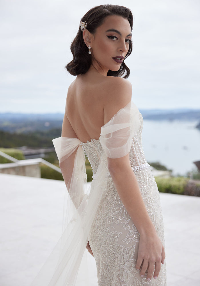 Close up of back of Tristan gown showing tulle off-shoulder sleeves and pearl detailing on bodice.