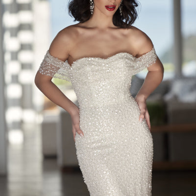 Tavi - a stunning form-fitting sheath gown with sequin and bead embellishments. Features a gathered and draped bodice, sweetheart neckline, and chapel length train. The V-shaped back adds an extra touch of elegance.