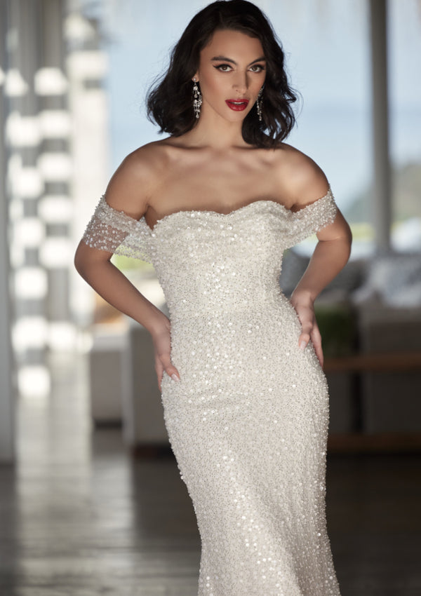 Tavi - a stunning form-fitting sheath gown with sequin and bead embellishments. Features a gathered and draped bodice, sweetheart neckline, and chapel length train. The V-shaped back adds an extra touch of elegance.