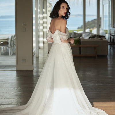 Tavi with tulle overskirt from the back with off the shoulder beaded sleeves 