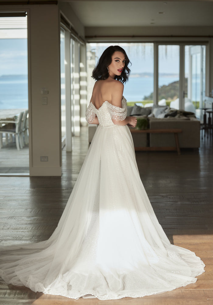 Tavi with tulle overskirt from the back with off the shoulder beaded sleeves 