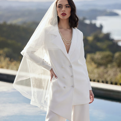 Ivory wedding blazer in asymmetric double-breasted cut. Worn with ivory trousers and veil.