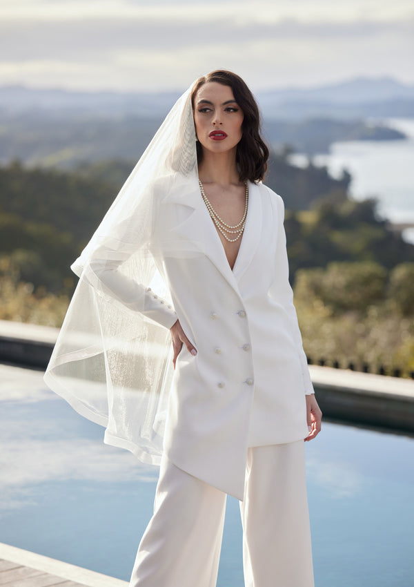 Ivory wedding blazer in asymmetric double-breasted cut. Worn with ivory trousers and veil.