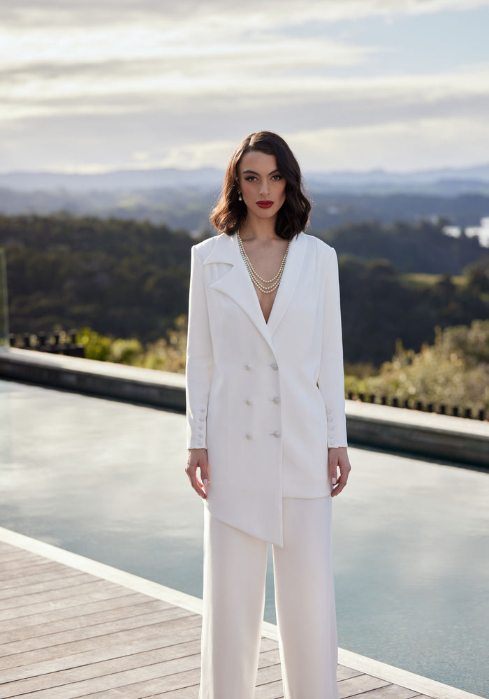 Ivory wedding blazer in asymmetric double-breasted cut. Worn with ivory trousers.