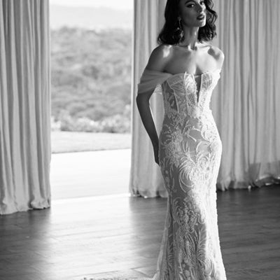 Black and white image of Tay gown. Heavily beaded trumpet silhouette gown with visible corsetry and soft tulle off the shoulder straps.