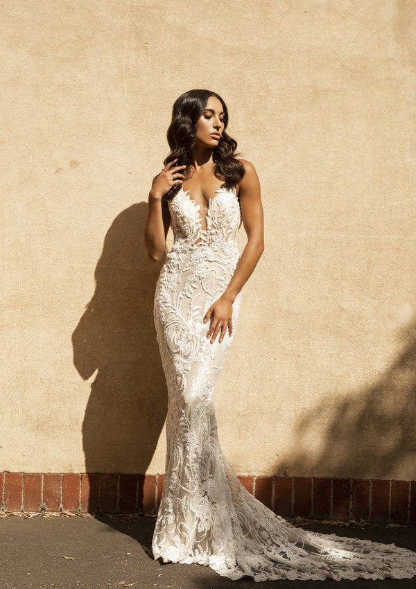 Nikola gown in fully-beaded lace on a fit-n-flare silhouette. Plunging v-neckline with lace stitched over illusion mesh. Beaded train.