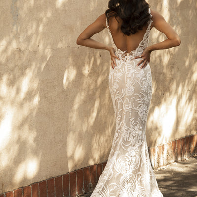 Back view of Nikola gown. Plunging back sits just above waistline. 3D embroidered and beaded lace covers entire gown leading to shaped train.