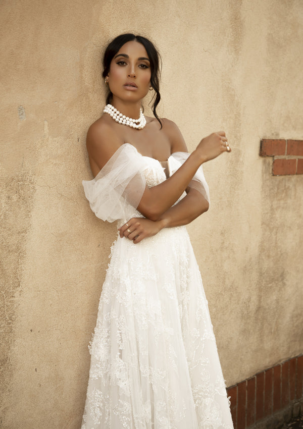 Soft a-line Rohini gown with heavily textured applique and soft tulle off-the-shoulder straps.
