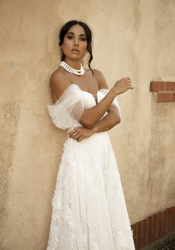Soft a-line Rohini gown with heavily textured applique and soft tulle off-the-shoulder straps.